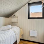 Schlafzimmer mit Bett, Wandregal und Fenster mit Blick auf Dach