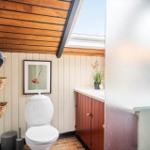 Badezimmer mit Toilette, Waschbecken und Dusche unter Holzdecke.