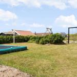 Grüner Garten mit Trampolin, Schaukel und Heckenzaun. Hintergrund: Häuser mit Dächern.