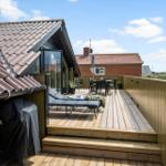 Terrasse mit Liegen, Tisch und Stühlen, Blick auf Wohnhaus und Strand.