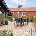 Terrasse mit Tisch, Stühlen und Sonnenschirm. Holzdecke und Blick auf roten Backsteinbau.