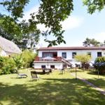 Haus mit Garten, Terrasse und Liegestühlen unter Bäumen.