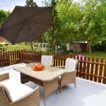 Terrasse mit Tisch, Stühlen und Sonnenschirm. Hinterhof mit Grünfläche und Zaun.
