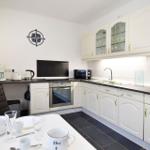 Küche mit weißen Schränken, dunkler Arbeitsplatte und Küchentisch mit Geschirr.