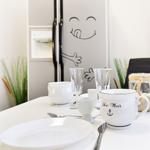 Küchenbereich mit Tisch, Geschirr und Kühlschrank mit Zeichnung.