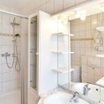 Badezimmer mit Dusche, Waschbecken und Spiegelschrank.