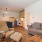 Wohnzimmer mit Sofa, Sessel und Küchenbereich.