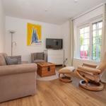 Wohnzimmer mit Sofa, Sessel, Fernseher und Holzboden.