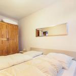 Schlafzimmer mit Doppelbett, Holzschrank und Spiegel an der Wand.