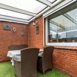 Terrasse mit Tisch, Stühlen und grünem Boden, an roten Ziegelwänden angebracht.