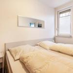 Schlafzimmer mit Doppelbett, Spiegel und Fenster mit Jalousie.