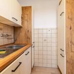 Küche mit Holzoberfläche, Spüle und weißen Schränken