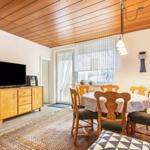 Wohn- und Essbereich mit Holzdecke, Esstisch, TV und Fenster.