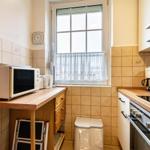 Küche mit Mikrowelle, Kaffeemaschine und Fenster mit Gardine.