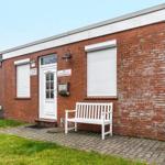 Rotes Backsteinhaus mit weißer Tür und Bank vorne.