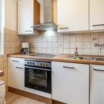 Küche mit weißen Schränken, Holzoberfläche und integriertem Ofen.