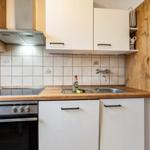 Küche mit weißen Schränken, Holzoberfläche und Edelstahlspüle.