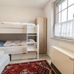 Zimmer mit Doppelstockbett, Kleiderschrank und Fenster mit Vorhang.