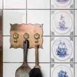 Wand mit Fliesen, Schiffsmotiven und Haken für Küchenutensilien