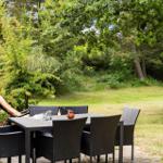 Terrasse mit Tisch, Stühlen und Liegestuhl im Grünen.