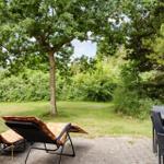 Terrasse mit Liegestühlen und Tisch unter Bäumen.