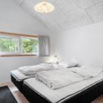 Schlafzimmer mit Doppelbett, Fenster und Deckenleuchte.