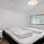 Schlafzimmer mit Doppelbett, Nachttisch und Fenster mit Blick auf Grün.