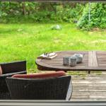 Terrasse mit Tisch, Stühlen und Blick auf grünen Rasen