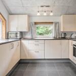 Küche mit hellen Schränken, Fenstern und moderner Ausstattung.