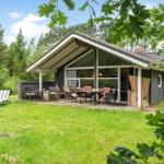 Ein Haus mit Terrasse, Garten und Liegestühlen unter Bäumen.