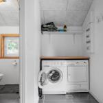 Waschraum mit Waschmaschine und Trockner. Nebenraum mit Toilette und Fenster.