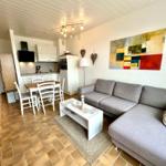 Wohn- und Küchenbereich mit Sofa, Esstisch und moderner Einbauküche.