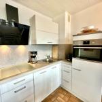 Küche mit weißen Schränken, Edelstahlgeräten und Arbeitsplatte.