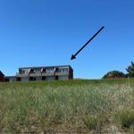 Modernes Gebäude mit Balkonen auf grünem Hang unter blauem Himmel