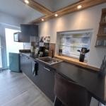 Moderne Küche mit dunklen Schränken, Holzbalken und Fenster mit Jalousie.