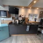 Küche mit dunklen Schränken, Küchenzeile und Kücheninsel mit Stuhl.