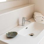 Waschbecken mit Chromhahn, Handtücher und Schale auf der Arbeitsfläche.