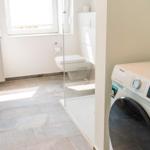 Badezimmer mit Waschmaschine, Toilette und Waschbecken.