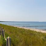Wanderweg entlang der Küste mit Strand und Gras.