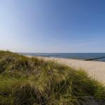 Strand mit Sanddünen und Meer unter blauem Himmel