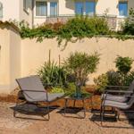 Terrasse mit Liegestühlen, Tisch und Stand-Up-Paddleboard an der Wand.