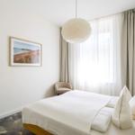 Schlafzimmer mit Bett, Stehlampe und Fenster mit Vorhängen.