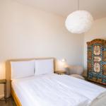 Schlafzimmer mit Bett, Nachttisch und farbenfroher Kommode.