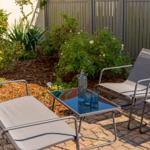 Terrasse mit drei Liegestühlen und Tisch mit blauen Gläsern.