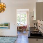 Küche mit Essbereich und Wohnzimmer mit Wandbild und Pendelleuchte.