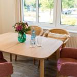 Essbereich mit Holztisch, Stühlen und Blumen am Fenster.