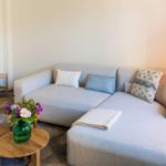 Ein grauer Sofa mit Kissen und einem Tisch mit Blumen.