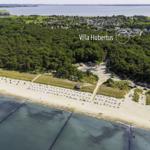 Villa Hubertus liegt am Strand mit Wald und See im Hintergrund.