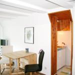 Wohn- und Küchenbereich mit Holztisch, Stühlen und Fenster