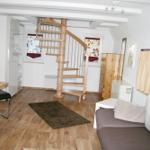 Wohnraum mit Couch, Tisch, Schreibtisch und Wendeltreppe.